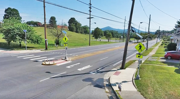 A photograph of a crossing at an intersection with RRFBs and a pedestrian refuge island.